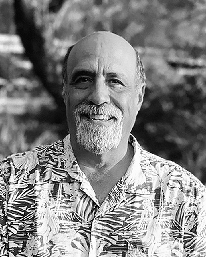 Black and white portrait of Tom Poblano, smiling, in an aloha shirt
